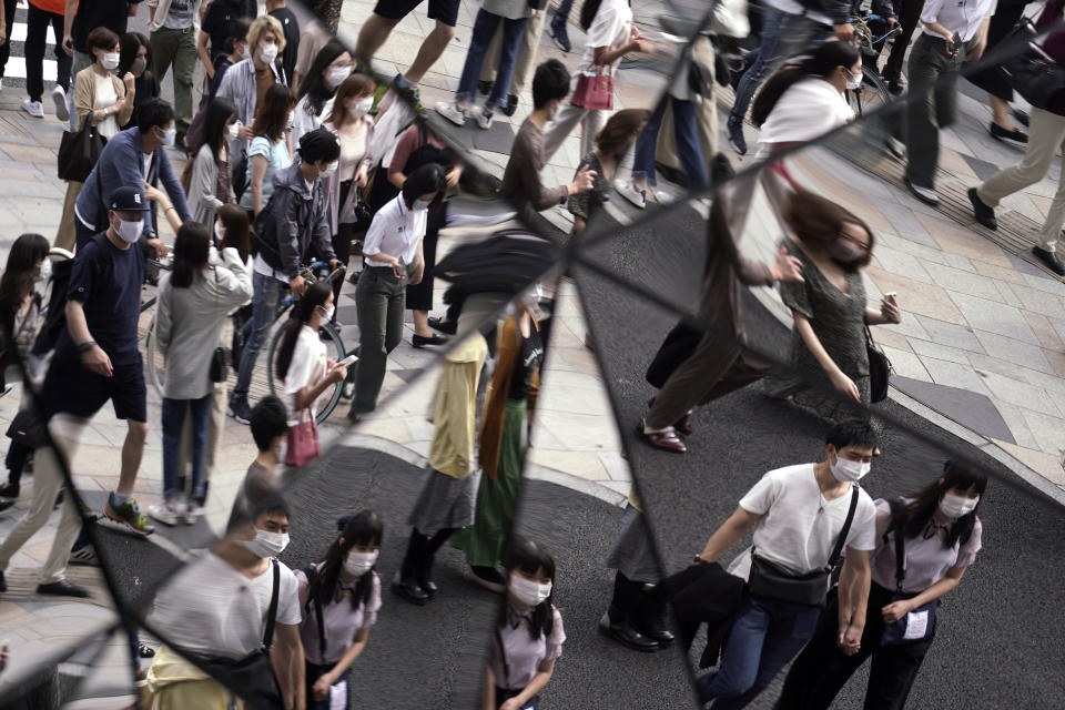 People wearing protective masks to help curb the spread of the coronavirus are reflected on mirror wall of a shopping building Monday, Sept. 21, 2020, in Tokyo. The Japanese capital confirmed more than 90 coronavirus cases on Monday marking Respect-for-the-Aged Day holiday. (AP Photo/Eugene Hoshiko)