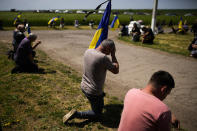 Mourners kneel as they await the coffin of Volodymyr Losev, 38, to pass by during his funeral in Zorya Truda, Odesa region, Ukraine, Monday, May 16, 2022. Volodymyr Losev, a Ukrainian volunteer soldier, was killed May 7 when the military vehicle he was driving ran over a mine in eastern Ukraine. (AP Photo/Francisco Seco)