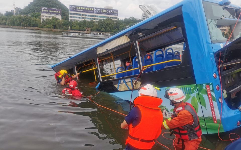 Rescue workers are seen at the site where a bus carrying students plunged into a lake  - REUTERS