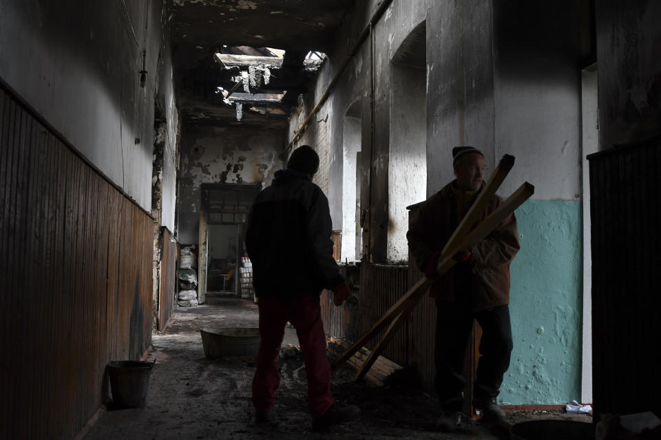 Workers clean up a school that was damaged from Russian shelling in the town of Orekhovo in Zaporizhzhya region, Ukraine, Monday, Jan. 30, 2023. (AP Photo/Andriy Andriyenko)