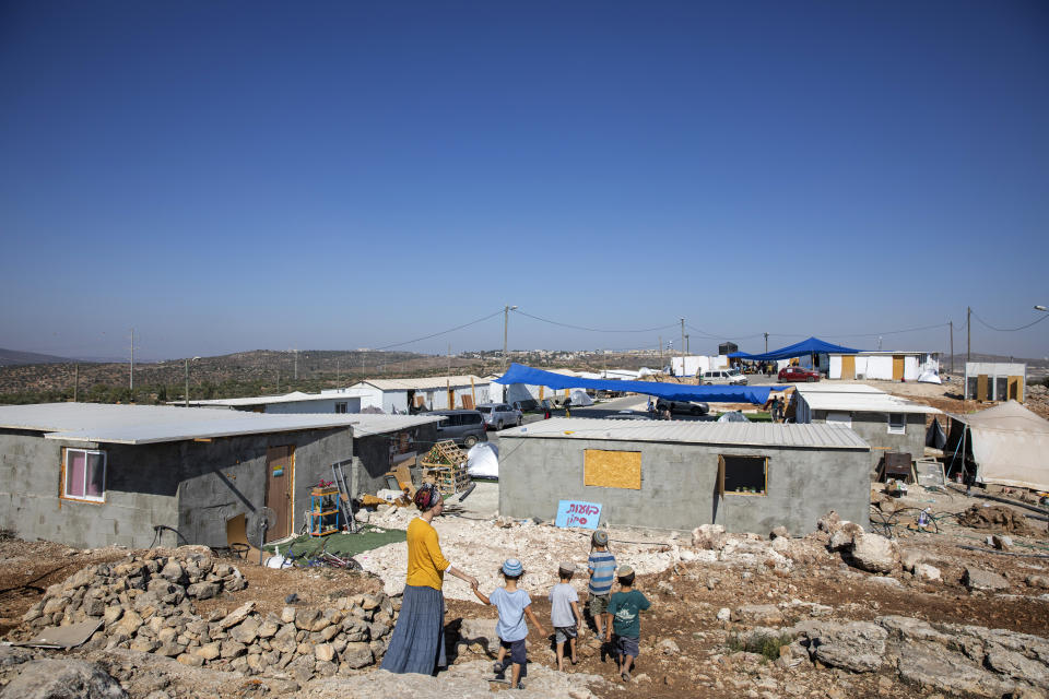 Israeli settlers walk at the recently established wildcat Jewish outpost of Eviatar, near the northern Palestinian West Bank town of Nablus, Monday, June 28, 2021. Palestinians say the outpost was established on private farmland. Israeli media said Monday that the government was working on reaching a compromise with the settlers that would see the outpost evacuated in the coming days. (AP Photo/Ariel Schalit)