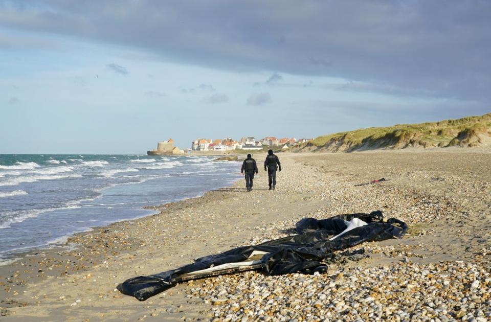 French police pass a deflated dighy on the beach in Wimereux near Calais  (PA)