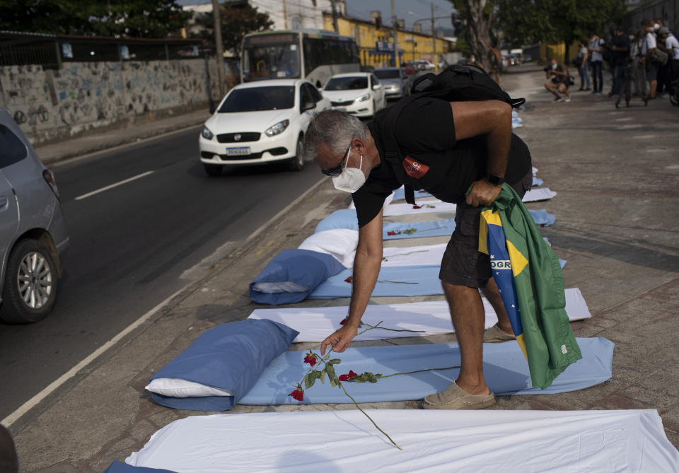 A demonstrator places roses on mattresses symbolizing COVID-19 victims, during a protest against the Government's handling of the COVID-19 pandemic, organized by the Rio de Paz NGO, in front of the Ronaldo Gazolla hospital in Rio de Janeiro, Brazil, Wednesday, March 24, 2021. (AP Photo/Silvia Izquierdo)