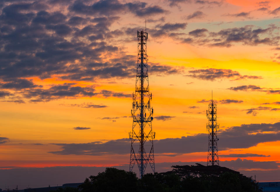 Cell towers with an orange sky behind them.