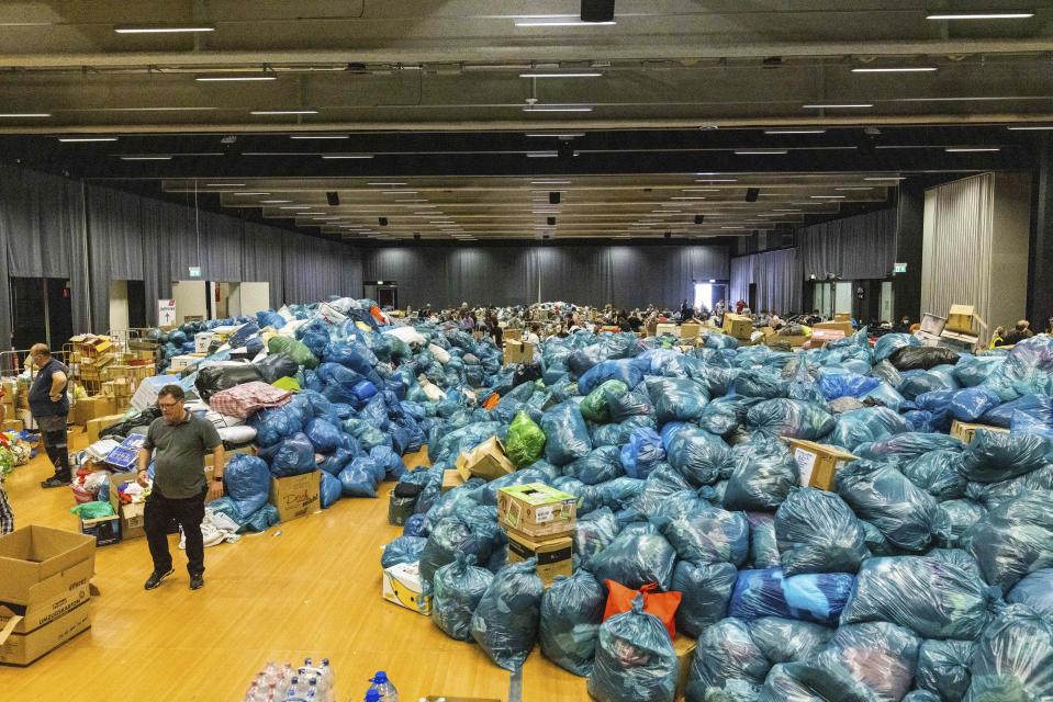 A person walks between donations in kind that are lying in a hall on the grounds of the Nuerburgring race track in Nuerburg, western Germany, Saturday, July 17, 2021. Heavy rains caused mudslides and flooding in the western part of Germany. Multiple have died and are missing as severe flooding in Germany and Belgium turned streams and streets into raging, debris-filled torrents that swept away cars and toppled houses. (Philipp von Ditfurth/dpa via AP)