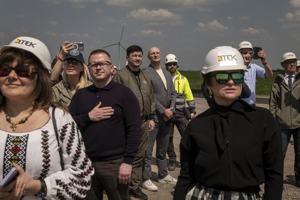 El gobernador de la región de Nicolaiev, Vitaliy Kim, al centro, vestido con una chaqueta con cremallera, y otras personas observan el evento de la ceremonia de inauguración del parque eólico de Tyligulska, en la región de Nikolaiev, Ucrania, el 18 de mayo de 2023. (Nicole Tung/The New York Times)
