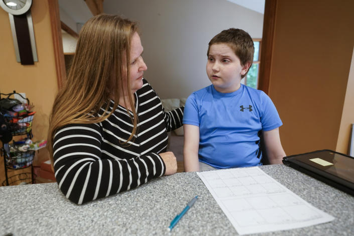 FILE - Lisa Manwell helps her son John Jinks, 12, with learning at their home in Canton, Mich., Wednesday, Sept. 21, 2022. The Education Department in May said that it intended to strengthen protections for students with disabilities through possible regulatory amendments to Section 504 of the Rehabilitation Act of 1973, which protects people from being discriminated against based on their disability. (AP Photo/Paul Sancya, File)