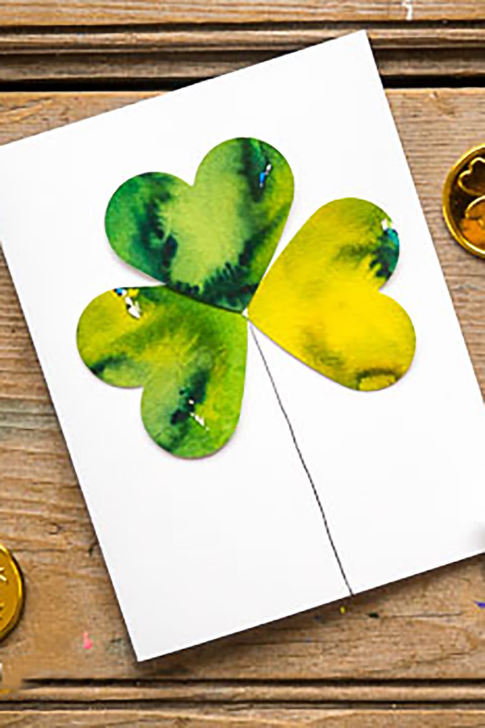 white card decorated with green watercolor shamrock made from three heart shaped paper cutouts