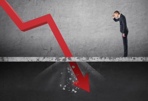 Businessman looking down at the falling red arrow destroying a concrete barrier.