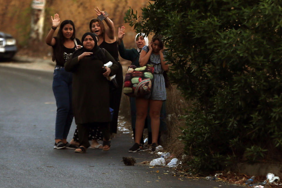 People carry their belongings as they gesture to Lebanese army soldiers after heavy clashes in the coastal town of Khaldeh, south of Beirut, Lebanon, Sunday, Aug. 1, 2021. At least two people were killed on Sunday south of the Lebanese capital when gunmen opened fire at the funeral of a Hezbollah commander who was killed a day earlier, an official from the group said. (AP Photo/Bilal Hussein)