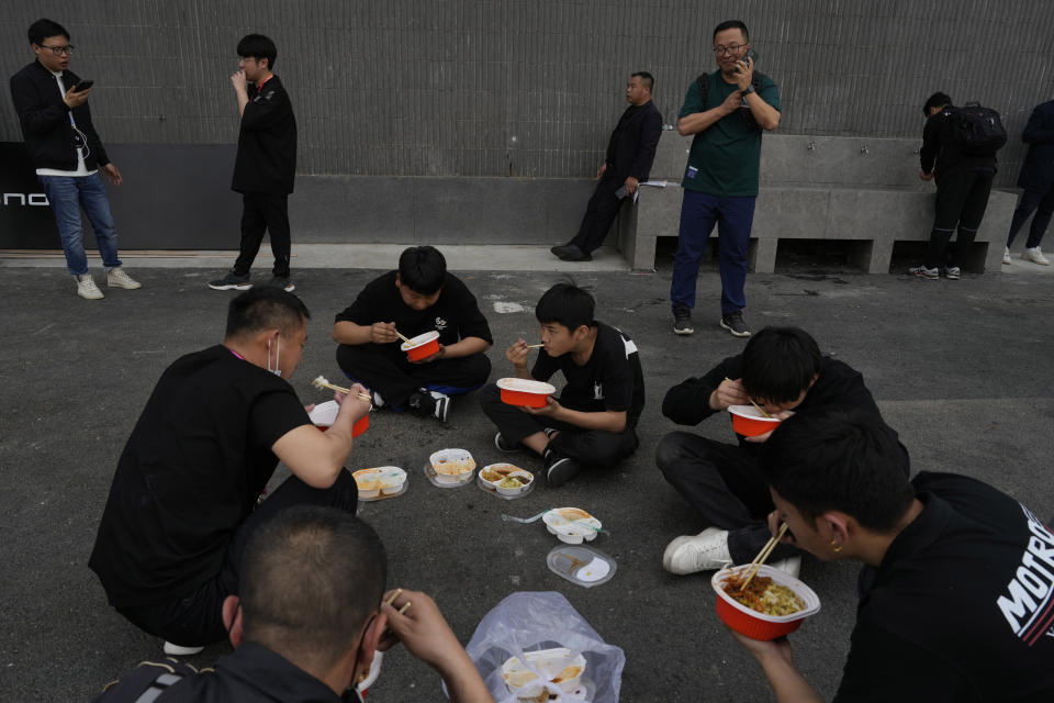 Workers take a lunch break during Auto China 2024 in Beijing, Thursday, April 25, 2024. Global automakers and EV startups unveiled new models and concept cars at China's largest auto show on Thursday, with a focus on the nation's transformation into a major market and production base for digitally connected, new-energy vehicles. (AP Photo/Ng Han Guan)