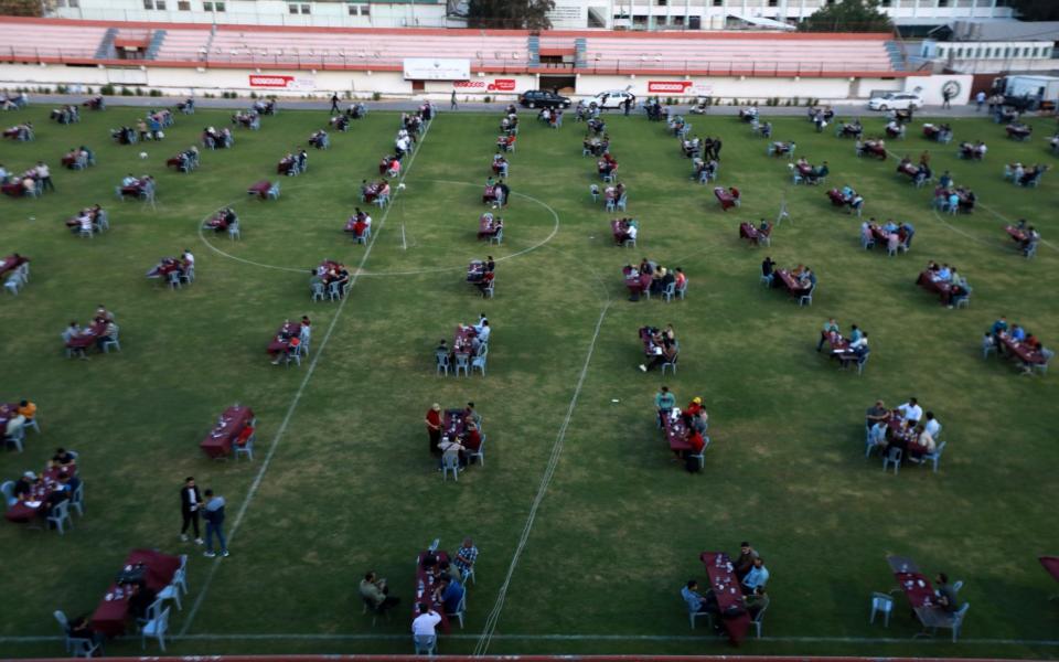 Palestinians break their Ramadan fast during an Iftar meal set-up to respect social distancing measures amid the COVID-19 pandemic, organized by the Islamic Hamas movement which runs the besieged Gaza Strip, at the Palestine football stadium in Gaza city