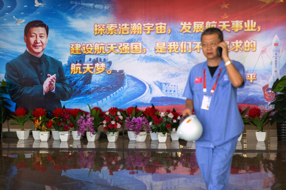 A worker walks past a billboard with a quotation from Chinese President Xi Jinping in a building at the Wenchang Space Launch Site in Wenchang in southern China's Hainan province, Monday, Nov. 23, 2020. Chinese technicians were making final preparations Monday for a mission to bring back material from the moon's surface for the first time in nearly half a century — an undertaking that could boost human understanding of the moon and of the solar system more generally. (AP Photo/Mark Schiefelbein)