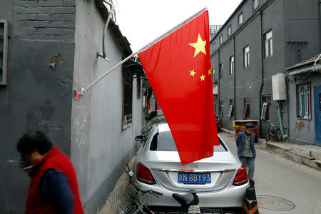 People walk at a hutong alley decorated with Chinese national flags during the ongoing 19th National Congress of the Communist Party of China, in Beijing, China October 21, 2017. REUTERS/Tyrone Siu/Files