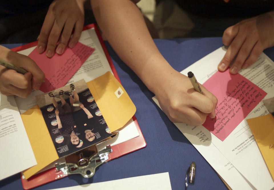 Daniel Kim, right, and Michael Chen write notes to accompany their photograph to go into a time capsule at the New-York Historical Society in New York, Sunday, June 2, 2019. The letters share LGBT life stories through the Generations Project, a project committed to preserve LGBTQ history. (AP Photo/Seth Wenig)