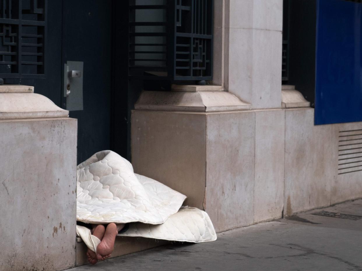 A homeless person sleeps on the pavement near a cash machine: Getty