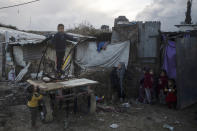 Palestinian children play outside their homes during a cold weather spell in a slum on the outskirts of the Khan Younis refugee camp, southern Gaza Strip, Wednesday, Jan. 19, 2022. (AP Photo/Khalil Hamra)