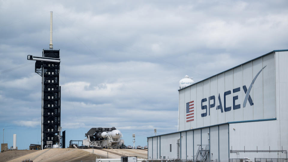 a white rocket heads out of its hangar toward the launch pad in a horizontal configuration.