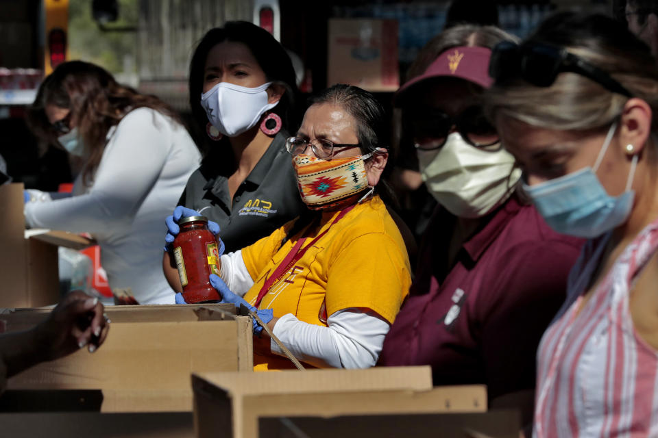 Volunteers prepare donations for delivery to those affected by COVID-19 on tribal lands Thursday, June 25, 2020, in Tempe, Ariz. The resource drive is for families isolated due to COVID-19 on Navajo, Hualapai, Havasupai and White Mountain Apache tribal lands. (AP Photo/Matt York)