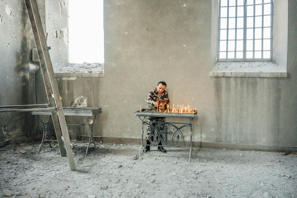 An Armenian soldier lights candles inside the Holy Savior Cathedral, which was damaged by shelling, in the town of Shusha outside Stepanakert.<span class="copyright">Emanuele Satolli</span>