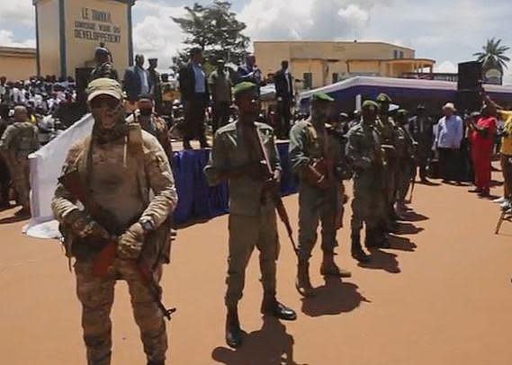 Masked Wagner Group mercenaries, along with domestic security agents, stand guard during an event as Central African Republic (CAR) President Faustin-Archange Touadéra speaks on stage, in September 2022. / Credit: CBS News