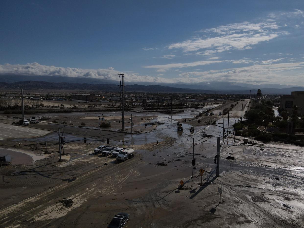 Crews operating heavy equipment work to clear mud and debris from the intersection of Bob Hope Drive and Ramon Road in Rancho Mirage on Monday.