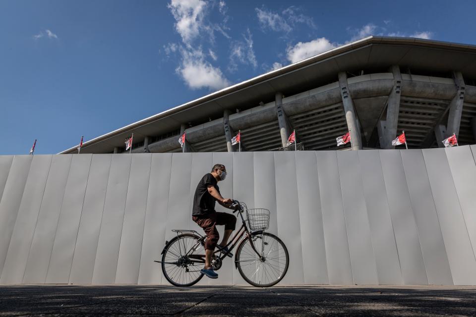 A man cycles past a security wall surrounding the International Stadium Yokohama (Getty Images)