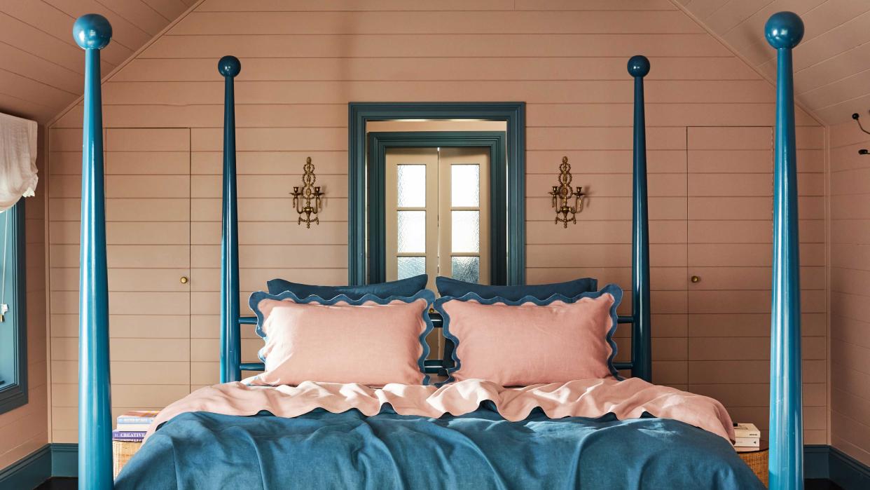  a pink bedroom with blue four poster bed 