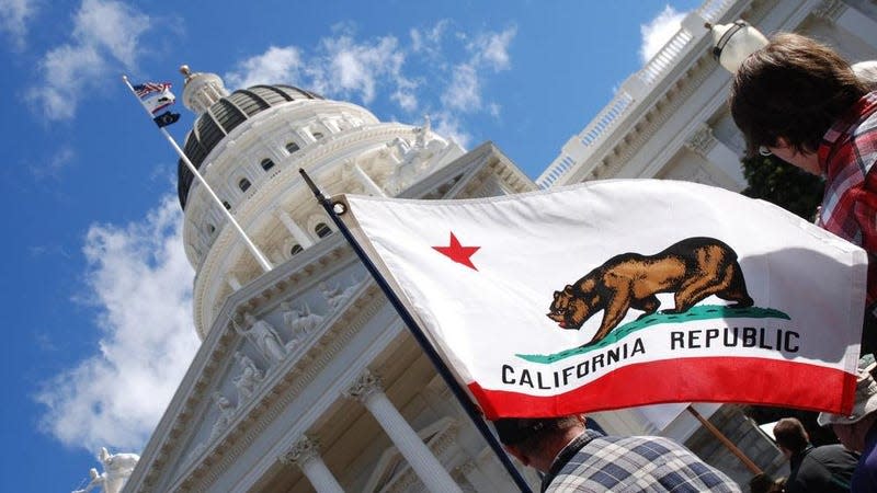 The California flag in front of the state capital. 