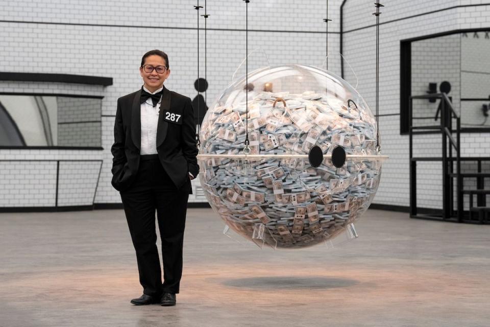 a person in a tuxedo standing next to a large sphere