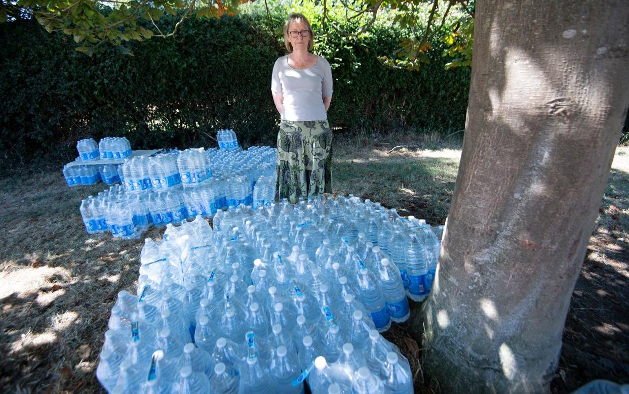 Carolyn Evans stands among the mass of water bottles piled on the village green - Eddie Mulholland 