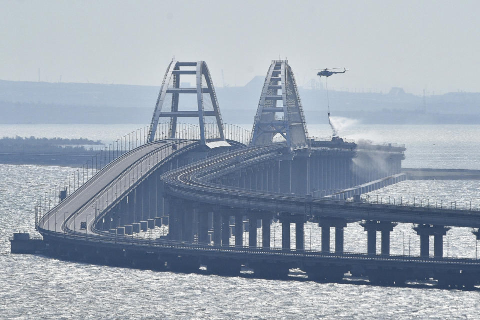 Un helicóptero arroja agua sobre un puente para sofocar un incendio, en el puente que conecta la península de Crimea con el territorio continental ruso sobre el estrecho de Kerch, en Kerch, el 8 de octubre de 2022. (AP Foto)