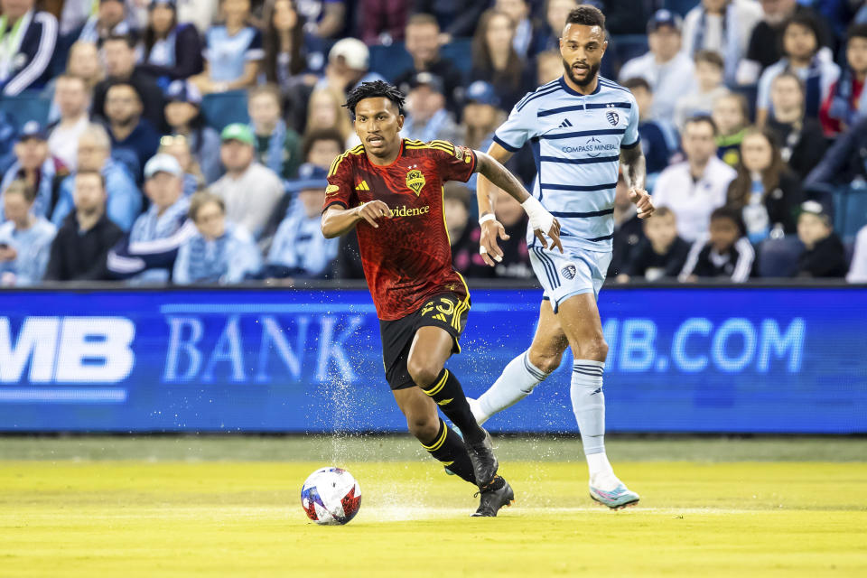 Seattle Sounders midfielder Leo Chu, left, attacks the ball past Sporting Kansas City forward Khiry Shelton, right, during the first half of an MLS soccer match Saturday, March 25, 2023, in Kansas City, Kan. (AP Photo/Nick Tre. Smith)