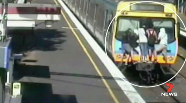 Youths riding the back of a moving train. Source: 7News