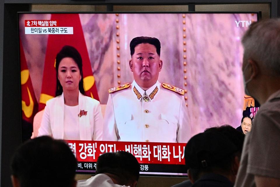 People sit in front of a screen showing a news broadcast with file footage of North Korean leader Kim Jong-un and his wife Ri Sol-ju, at a railway station in Seoul on June 5, 2022. - North Korea launched multiple ballistic missiles into waters off its east coast on June 5, South Korea's military said, a day after Seoul and Washington completed their first joint drills involving a US aircraft carrier in more than four years. (Photo by Anthony WALLACE / AFP) (Photo by ANTHONY WALLACE/AFP via Getty Images)
