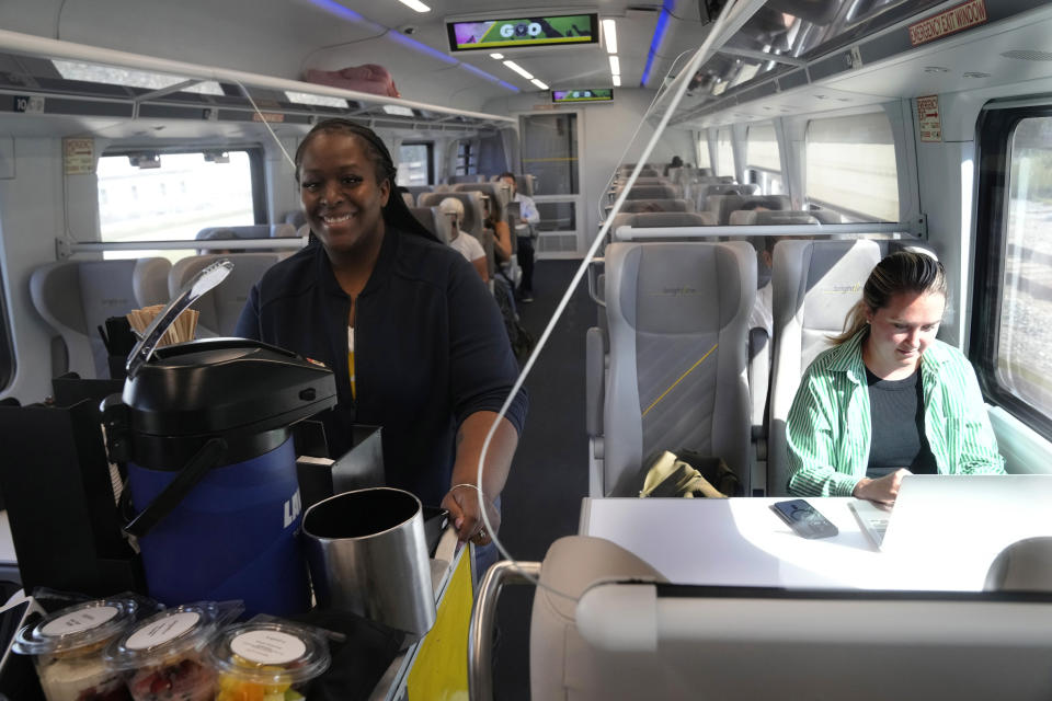 A Brightline employee sells drinks and snacks onboard a train, Friday, Sept. 8, 2023, in Fort Lauderdale, Fla. Brightline, is the first privately owned company to offer intercity service in the U.S. in over a century. The Florida trains, which run on biodiesel, will travel up to 79 mph (127 kph) in urban areas, 110 mph (177 kph) in less-populated regions and 125 mph (200 kph) through central Florida's farmland. (AP Photo/Marta Lavandier)