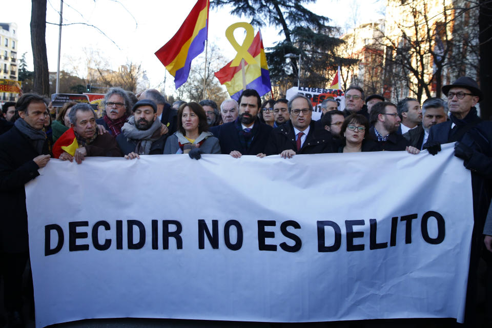 El presidente del Parlamento de Cataluña, Roger Torrent (centro), y el del gobierno regional, Quim Torra (centro derecha), posan con un cartel con el lema "Decidir no es delito", en el exterior del Tribunal Supremo, en Madrid, el 12 de febrero de 2019, en el inicio del juicio contra líderes independentistas. (AP Foto/Andrea Comas)