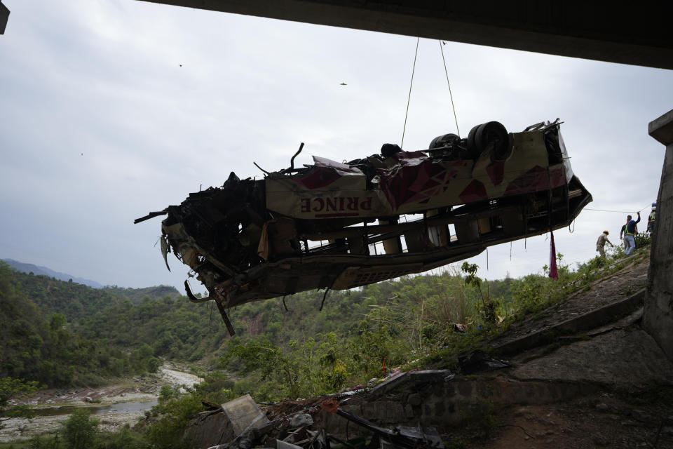 Rescuers use a crane to lift after a bus carrying Hindu pilgrims to a shrine skid off a highway bridge into a Himalayan gorge near Jammu, India, Tuesday, May 30, 2023. (AP Photo/Channi Anand)