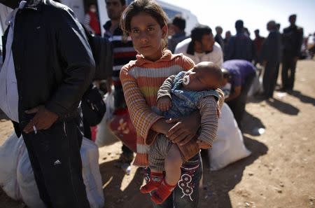 Rula, an eight-year-old Syrian Kurdish refugee girl holding her three-month-old brother Ciwan, waits for transportation after crossing into Turkey near the southeastern Turkish town of Suruc in Sanliurfa province October 1, 2014. REUTERS/Murad Sezer
