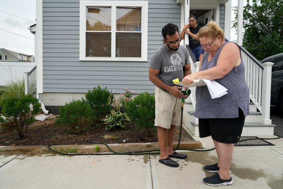 Linda Perri, president of the Washington Park Neighborhood Association, signs up homeowners Jose and Gladys Mayi to have trees planted around their Pavilion Street home to provide some cooling shade.