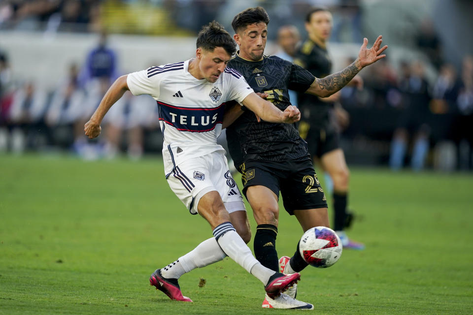 Vancouver Whitecaps midfielder Alessandro Schoepf, left, shoots against Los Angeles FC forward Cristian Olivera during the first half of an MLS playoff soccer match Saturday, Oct. 28, 2023, in Los Angeles. (AP Photo/Ryan Sun)