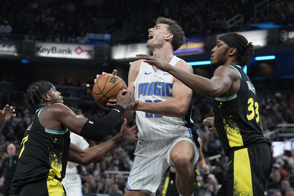 Orlando Magic's Franz Wagner (22) is defended by Indiana Pacers' Buddy Hield, left, and Myles Turner during the first half of an NBA basketball game Saturday, Dec. 23, 2023, in Indianapolis. (AP Photo/Darron Cummings)