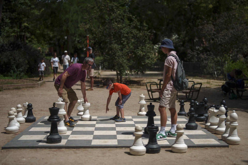 People play chess during a hot and sunny day at the Retiro park in Madrid, Spain, Monday, July 17, 2023. Spain’s Aemet weather agency said the heat wave this week “will affect a large part of the countries bordering the Mediterranean“ with temperatures in some southern areas of Spain exceeding 42 C (107 F). (AP Photo/Manu Fernandez)