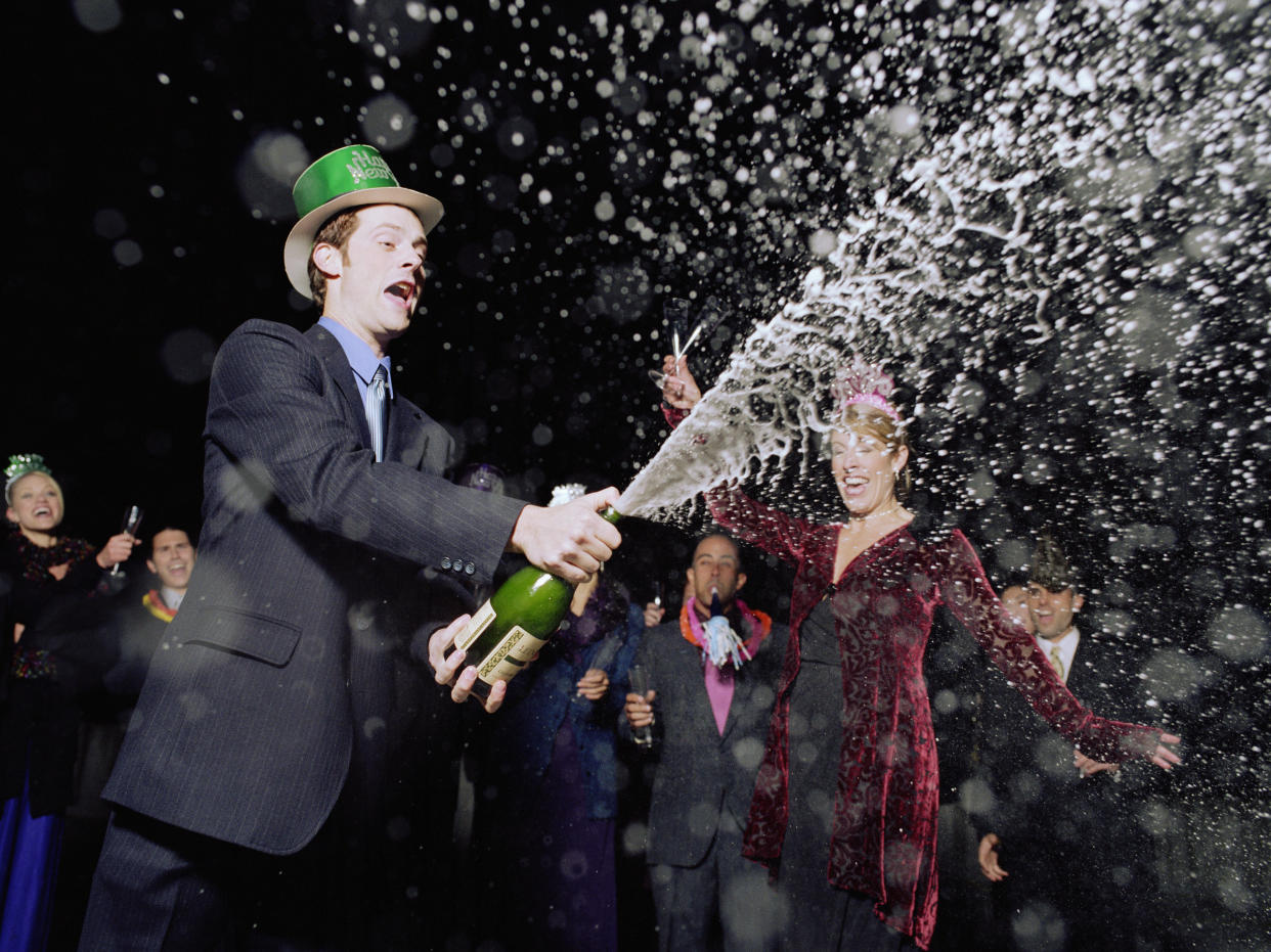 A man sprays a bottle of champagne at a New Year's Eve party in Los Angeles. (Photo: Getty Images)