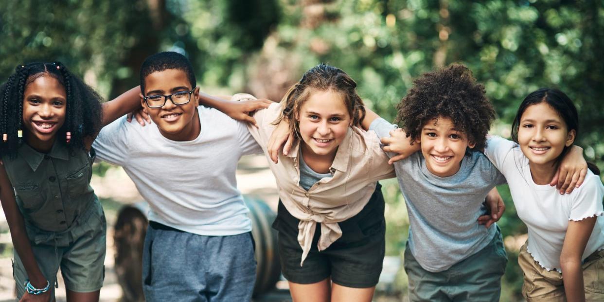 shot of a group of teenagers embracing in nature at summer camp