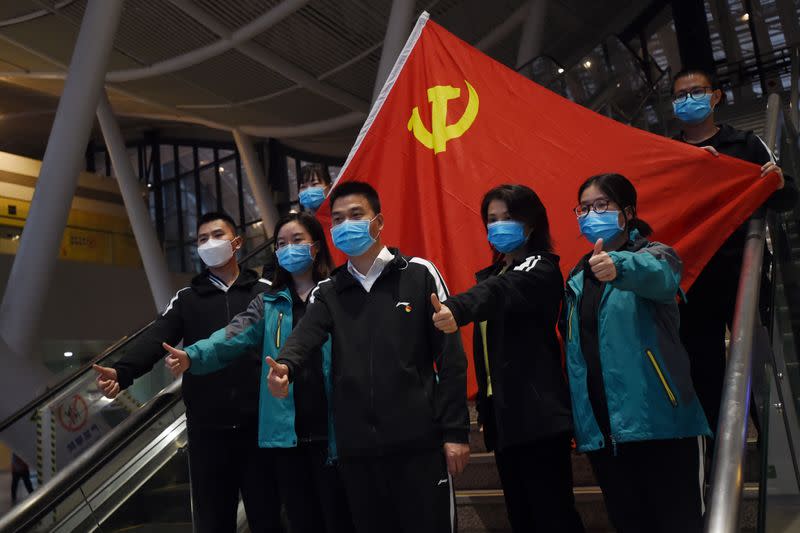 Medical workers from outside Wuhan pose for pictures with a Chinese Communist Party flag at the Wuhan Railway Station before leaving the epicentre of the novel coronavirus disease outbreak