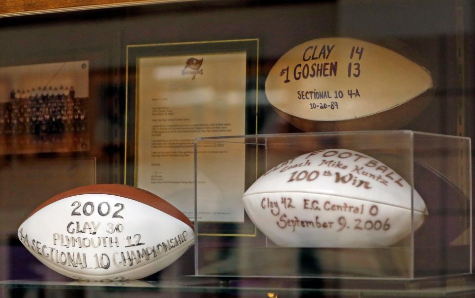 A display case inside South Bend Clay High School showcases game balls from three of its biggest wins in football program history.