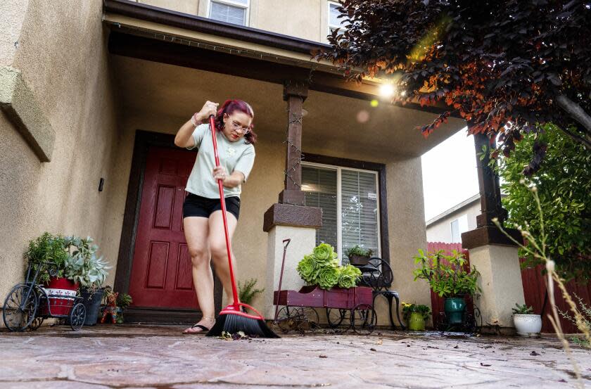 VICTORVILLE, CA - JULY 5, 2023: Gladis Avila still finds time to sweep her front porch after commuting five days a week from her home in Victorville to her job as a housekeeper at the W hotel in Hollywood on July 5, 2023 in Victorville, California. She lives in Victorville with her husband and three children.(Gina Ferazzi / Los Angeles Times)