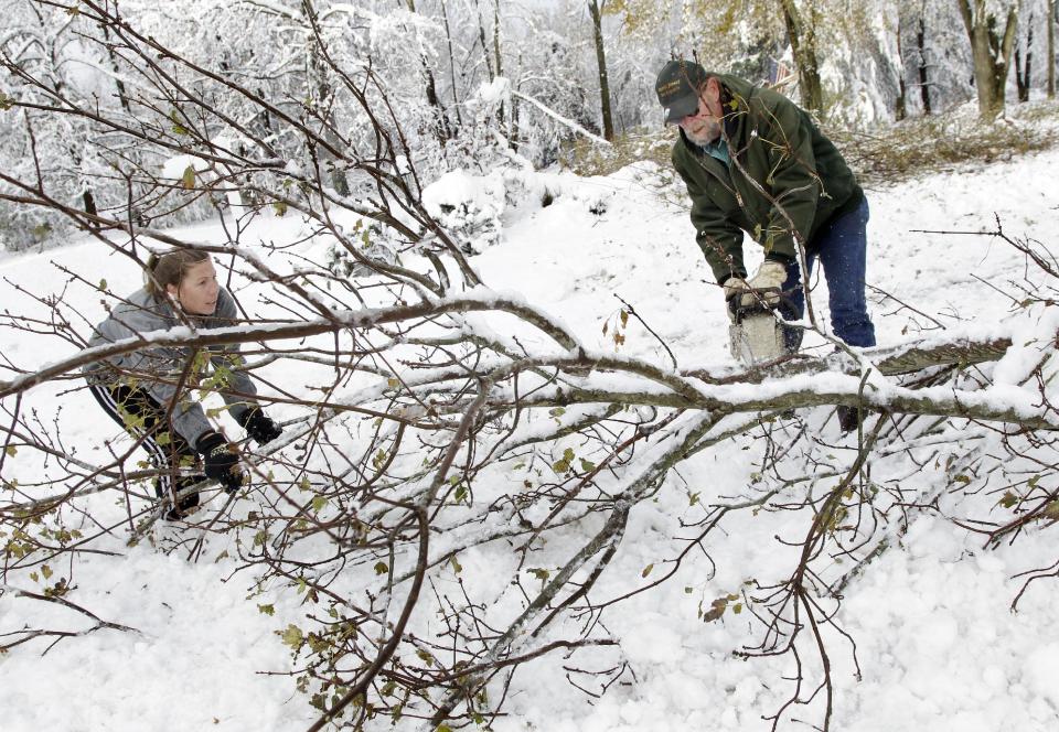 Bob Quakenbush and his daughter Dana Letual clear a fallen tree from his driveway so he can go to work Thursday, Nov. 8, 2012, in Millstone Township, N.J. The New York-New Jersey region woke up to a layer of wet snow and more power outages after a new storm pushed back efforts to recover from Superstorm Sandy.(AP Photo/Mel Evans)