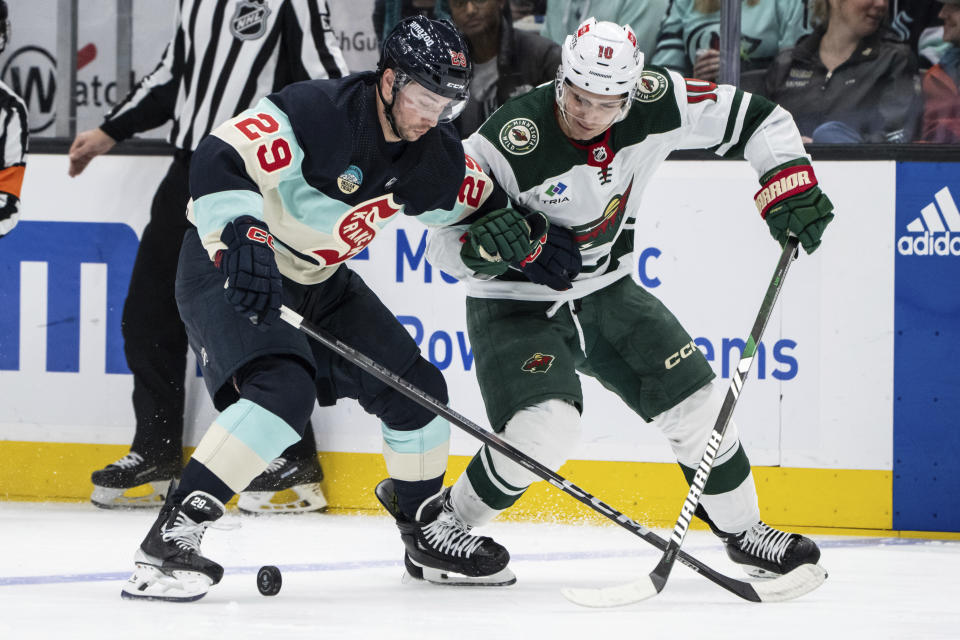 Seattle Kraken defenseman Vince Dunn, left, and Minnesota Wild forward Vinni Lettieri vie for the puck during the third period of an NHL hockey game Saturday, Feb. 24, 2024, in Seattle. (AP Photo/Stephen Brashear)